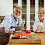 Older couple in kitchen holding wine glasses